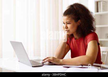 Nachdenkliche afroamerikanische Studentin, die ihren Laptop ernst ansieht Stockfoto