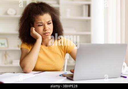 Müde oder frustrierte afroamerikanische Studentin, die mit ihrem Laptop unglücklich aussieht Stockfoto