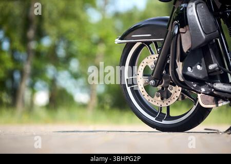 Details zu Tourenmotorrädern. Motorradvorderteil Nahaufnahme selektiver Fokus mit Kopierraum. Vorderrad mit Schild, Gabel, Bremssättel, Bremsscheibe Stockfoto