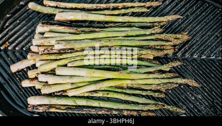 Ein Haufen Spargel ist auf dem Grill. Der Spargel ist grün und wird gekocht Stockfoto