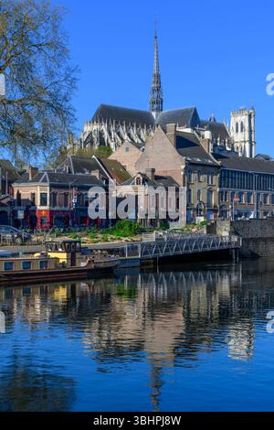 Binnenschiffe säumen den Rand des malerischen Flusses Somme in Amiens mit der herrlichen Kathedrale Amens Notre Dame im Hintergrund. Stockfoto