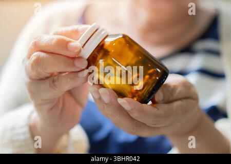 Eine ältere Frau sitzt an einem Tisch und hält die Flasche Pillen in der Hand. Alter Senioren Pharmazeutisches Gesundheitsbehandlungskonzept Stockfoto