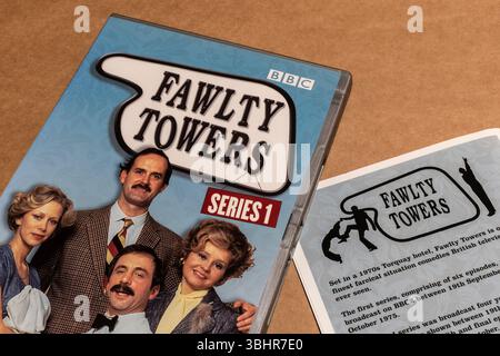 DVD-Box von Fawlty Towers mit den Hauptfiguren auf dem Cover und einem Flyer auf einem leeren Hintergrund Stockfoto