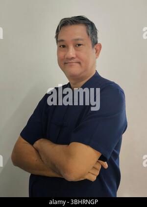 Asiatischer Mann mittleren Alters in tiefblauem Morhom-Hemd, traditionellem Textil aus Nordthailand. Stockfoto
