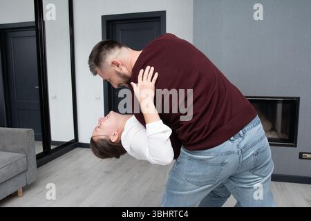 In einem stilvollen Wohnzimmer genießt ein glückliches Paar seine Zeit, tanzt mit Freude und Lachen, feiert seine Verbindung und schafft eine wertvolle Erinnerung Stockfoto