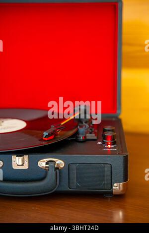 Vintage-Plattenspieler im Koffer-Stil, der Vinyl-Schallplatte dreht. Retro-Musik in Bewegung schafft nostalgische Atmosphäre im Innenraum Stockfoto