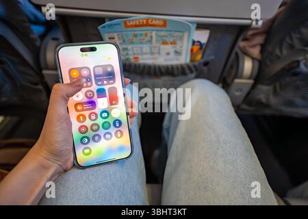 Prag, Tschechische republik - 7. Mai 2025: Frau aktiviert den Flugzeugmodus auf dem iPhone, während sie vor dem Start im Flugzeug sitzt. Digitale Trennung und Reisen Stockfoto