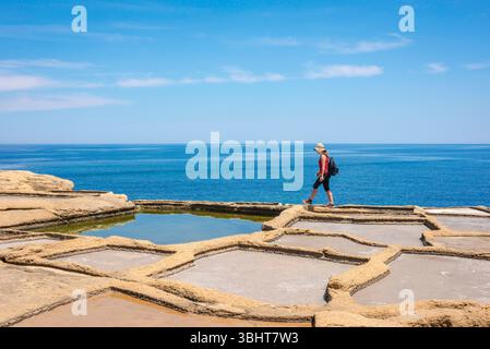 Saline Pans Malta, Blick auf eine junge Reisende, die die alten Salinen in der Bucht von Xwejni an der Nordküste von Gozo, Malta, erkundet. Stockfoto