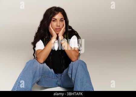 Eine junge Frau drückt ihre einzigartige Ästhetik aus, während sie bequem und nachdenklich sitzt. Stockfoto