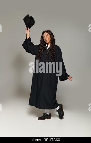 Der junge und schöne Schüler strahlt Glück aus, während er den Abschluss in formeller Kleidung feiert. Stockfoto