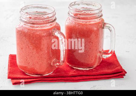 Cremiger tropischer Smoothie mit Kirsche, Banane und Ananas in einmachgläsern Stockfoto