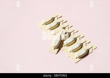 Zäpfchen in Blisterpackung auf Rosa angeordnet. Medizinische und pharmazeutische Konzepte. Stockfoto