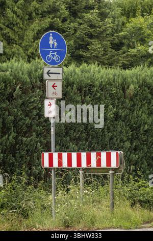 Borken, NRW, Deutschland, rot-weiß gestreiftes Straßensperrschild und gemeinsames Wegschild für Fußgänger und Radfahrer mit unterschiedlichen Wegbeschreibungen, EU Stockfoto