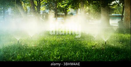 Sprinkler, die grünes Gras in einem Stadtpark in Taschkent, Usbekistan, bewässern. Automatisiertes Bewässerungssystem im Einsatz Stockfoto