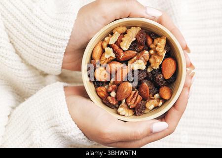 Gemischte Nüsse und Rosinen. Die Schale wird in gemütlichen Händen gehalten. Snack-Mischung auf dem natürlichen Trail. Gesunde Energie Booster. Vegane Protein-Combo. Sorte getrocknete Früchte. Stockfoto