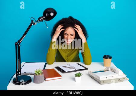 Junge Frau, die an einem Schreibtisch arbeitet und Stress und Frustration in einem professionellen Umfeld mit modernem Zubehör erlebt Stockfoto