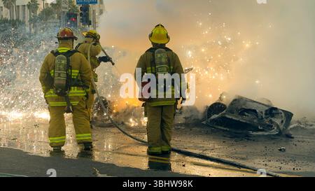 Los Angeles, USA. Juni 2025. Ein Bild, das am 11. Juni 2025 zur Verfügung gestellt wurde, zeigt elektrische Funken, die fliegen, während Feuerwehrleute fahrerlose Robo-Taxis während eines Protests gegen Einwanderungsrazzien der ICE und der Bundespolizei in Los Angeles löschen. Quelle: Zin Chiang/dpa/Alamy Live News Stockfoto