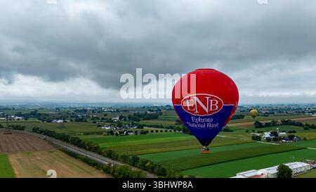 Bird in Hand, Pennsylvania, 13. September 2024 - bunte Heißluftballons schweben über üppiges Ackerland in Pennsylvania. Die Aussicht fängt das Flickenteppich von Feldern und entfernten Häusern unter einem bewölkten Himmel ein und bietet eine ruhige Atmosphäre. Stockfoto