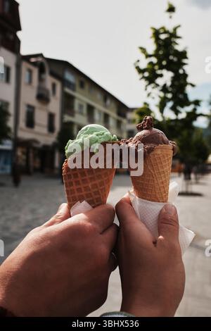 Zwei Leute, die Schokolade und Minzeiskrem im Stadtzentrum anstoßen. Das Konzept der Sommersüße und -Freuden. Stockfoto
