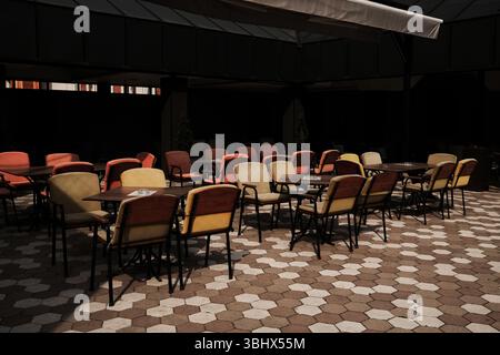 Leere farbenfrohe Kaffeesessel im Freien auf einem gemusterten Bürgersteig in Serbien. Stockfoto