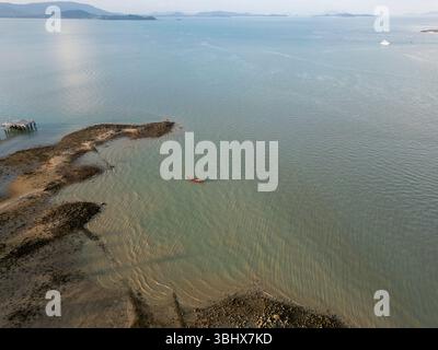 Blick aus der Vogelperspektive auf hölzerne Segelboote vor Anker an einer tropischen Inselküste, malerische Küstenszene mit Booten auf blauem Wasser in der Nähe des Strandes. Exotische Landschaft. Stockfoto