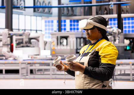 afroamerikanischer Ingenieur, der während der industriellen Ausbildung mit Virtual-Reality-Technologie interagiert. Werksleiter mit Produktsimulation für die Handhabung von VR-Headsets im Industrie-4,0-Lager. Stockfoto
