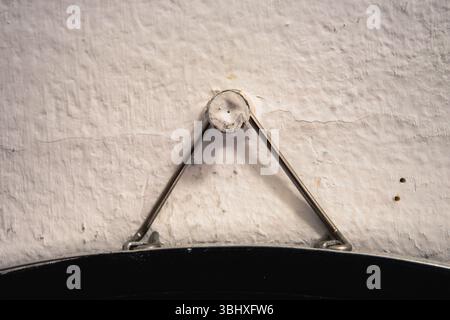 Metallrahmenstütze hing an einem Nagel in einer alten weißen Wand. Stockfoto