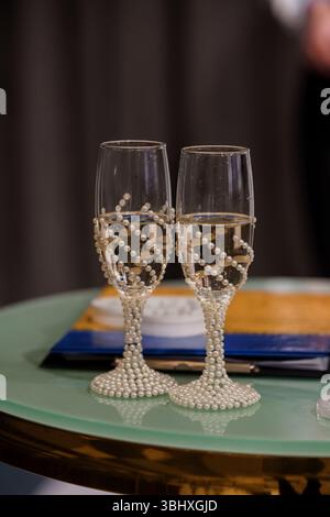 Intime Aufnahme von zwei Sektflöten, die mit zarten Perlen verziert sind, symbolisieren Feier, Liebe und Hochzeitstoast. Raffinierte und glamouröse aes Stockfoto