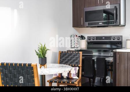 Küchentisch, gewebte Stühle und moderne Geräte in einem Ferienhaus Innenraum Stockfoto