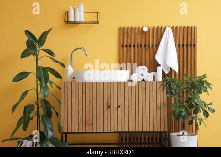 Saubere Handtücher hängen an der gelben Wand neben dem modernen Waschbecken im Badezimmer Stockfoto