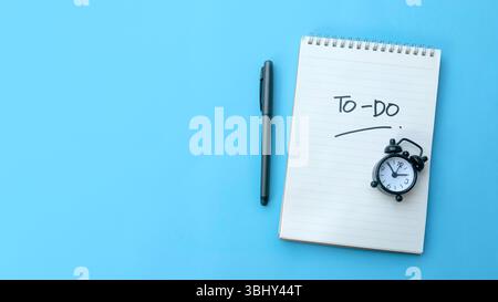 Aufgabenliste mit Stift und Wecker auf blauem Hintergrund Stockfoto