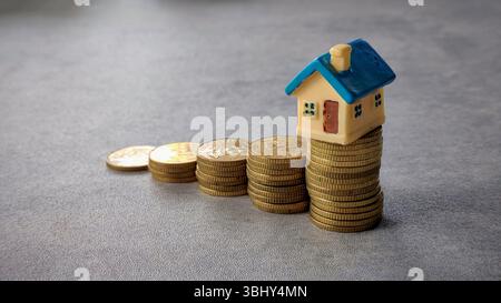 Modellhaus über Münzstapel, die Immobilieneinsparungen und Finanzwachstum hervorheben Stockfoto