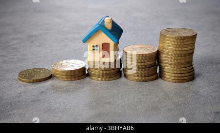 Modellhaus über Münzstapel, die Immobilieneinsparungen und Finanzwachstum hervorheben Stockfoto