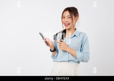 Glückliche asiatische Frau, die mit einer Hand auf das Telefon zeigt, während sie das Telefon selbstbewusst hält Stockfoto