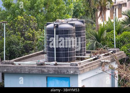 Zwei schwarze Kunststoff-Wassertanks auf dem Dach eines Wohngebäudes in Bangladesch. Stockfoto
