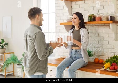 Glückliches freundliches, liebevolles junges Ehepaar, das sich in moderner, stilvoller Küche unterhalten kann Stockfoto