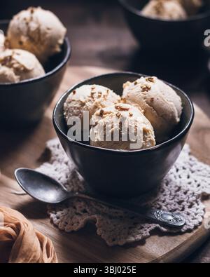 Eine Schüssel cremiges Erdnussbutter-Eis mit griechischem Joghurt und frischer Sahne. Dieses Dessert mit knusprigen Nüssen ist perfekt für einen Sommergenuss Stockfoto
