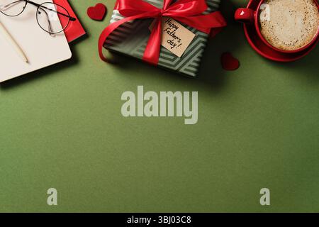 Happy Vatertag Flat-Lay-Konzept. Geschenkbox, Kaffeetasse, Brille und Notizbuch auf grünem Hintergrund. Draufsicht Stockfoto