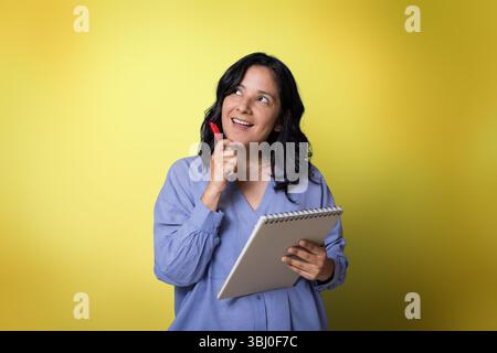 Junge Erwachsene Frau im Alter von 40 Jahren, die Notizen auf Notizbuch mit Stift macht. Stockfoto