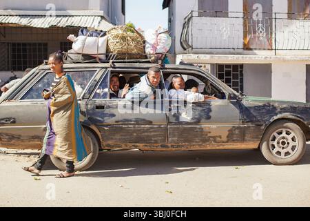 Ilakaka, Madagaskar - 30. April 2019: Altes, rostiges Auto mit vielen Einheimischen, die an hellen Tagen auf einer staubigen Straße fahren. Nicht viele Leute besitzen hier ein Auto als Pop Stockfoto