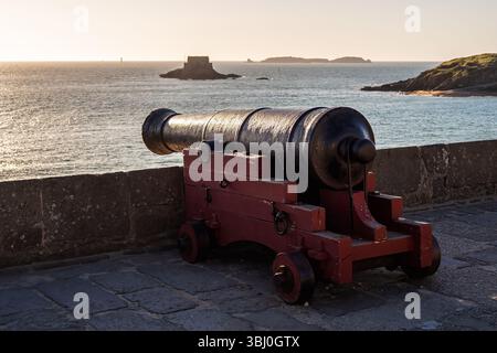 Alte Eisenkanone auf den Steinmauern der historischen Küstenfestung Saint-Malo, Bretagne, Frankreich. Malerischer Blick auf den Ärmelkanal bei Sonnenuntergang. Stockfoto