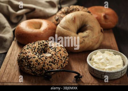 Verschiedene Bagels mit Cream Cheese-Aufstrich, auf Holztisch. Lebensmittelfotografie Im Rustikalen Stil Stockfoto
