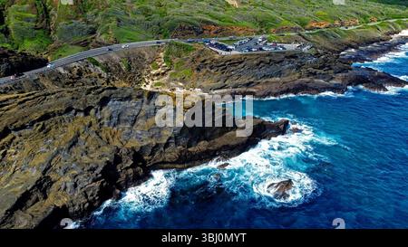 Blick aus der Vogelperspektive auf die zerklüfteten hawaiianischen Küstenklippen. Ein atemberaubender Blick aus der Vogelperspektive auf die felsige Küste Hawaiis mit dramatischen vulkanischen Klippen und dem stürzenden Ozean Stockfoto