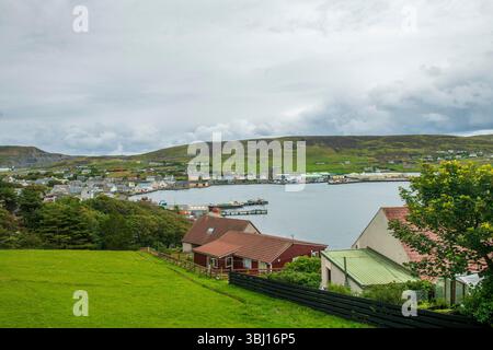Scalloway, die ehemalige Hauptstadt von Shetland, verbindet reiche Geschichte, farbenfrohe Hafenleben und dramatische Küstenschönheiten in einem unvergesslichen Dorf. Stockfoto
