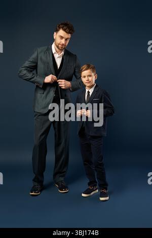 In passenden Anzügen teilen ein Vater und ein Sohn einen Moment der Freude und Verbundenheit. Stockfoto