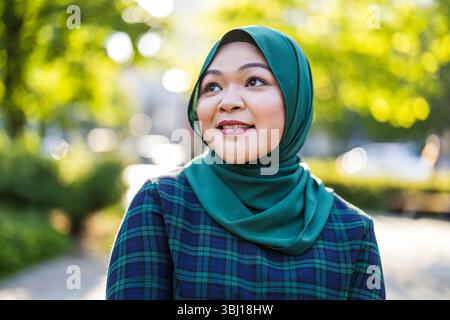 Porträt einer asiatischen muslimischen Frau, die Hijab trägt und vor der Kamera lächelt Stockfoto
