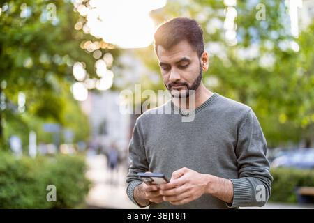 Porträt eines jungen Mannes, der sein Handy in der Stadt benutzt Stockfoto