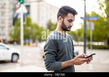 Porträt eines jungen Mannes, der sein Handy in der Stadt benutzt Stockfoto