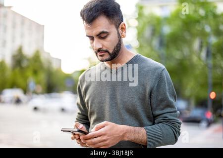 Porträt eines jungen Mannes, der sein Handy in der Stadt benutzt Stockfoto