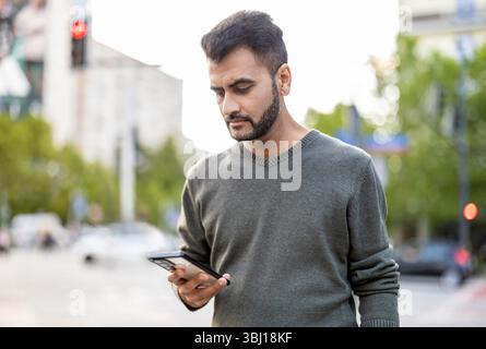 Porträt eines jungen Mannes, der sein Handy in der Stadt benutzt Stockfoto